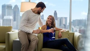 A couple sitting on a sofa with a cityscape view in the background. - Hollywood Casino at Greektown (Detroit)
