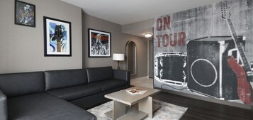 Una sala moderna con un sofá de cuero negro, una mesa de centro, obras de arte enmarcadas en las paredes y un cartel grande en la pared.
