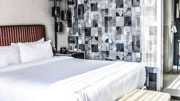 Una habitación de hotel moderna con una cama grande, una mesita de noche, un teléfono en la pared y una cortina estampada.