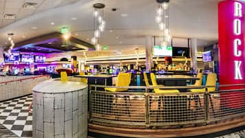 A bar area with a checkered floor, a drum, and a neon sign reading "ROCK".
