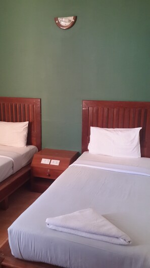 A hotel room with two single beds, wooden headboards, and a green wall. - Chaweng Inn (Koh Samui)