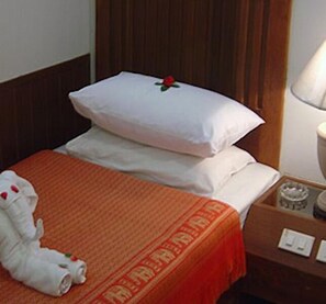 A hotel room with a bed, a nightstand, a lamp, and a towel on the floor. - Chaweng Inn (Koh Samui)
