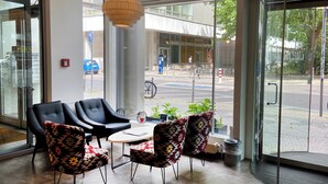 A modern interior with a glass door leading outside, featuring black and patterned chairs, a small table, and a hanging light fixture. - Garner Hotel Berlin - Gendarmenmarkt by IHG (Berlin)