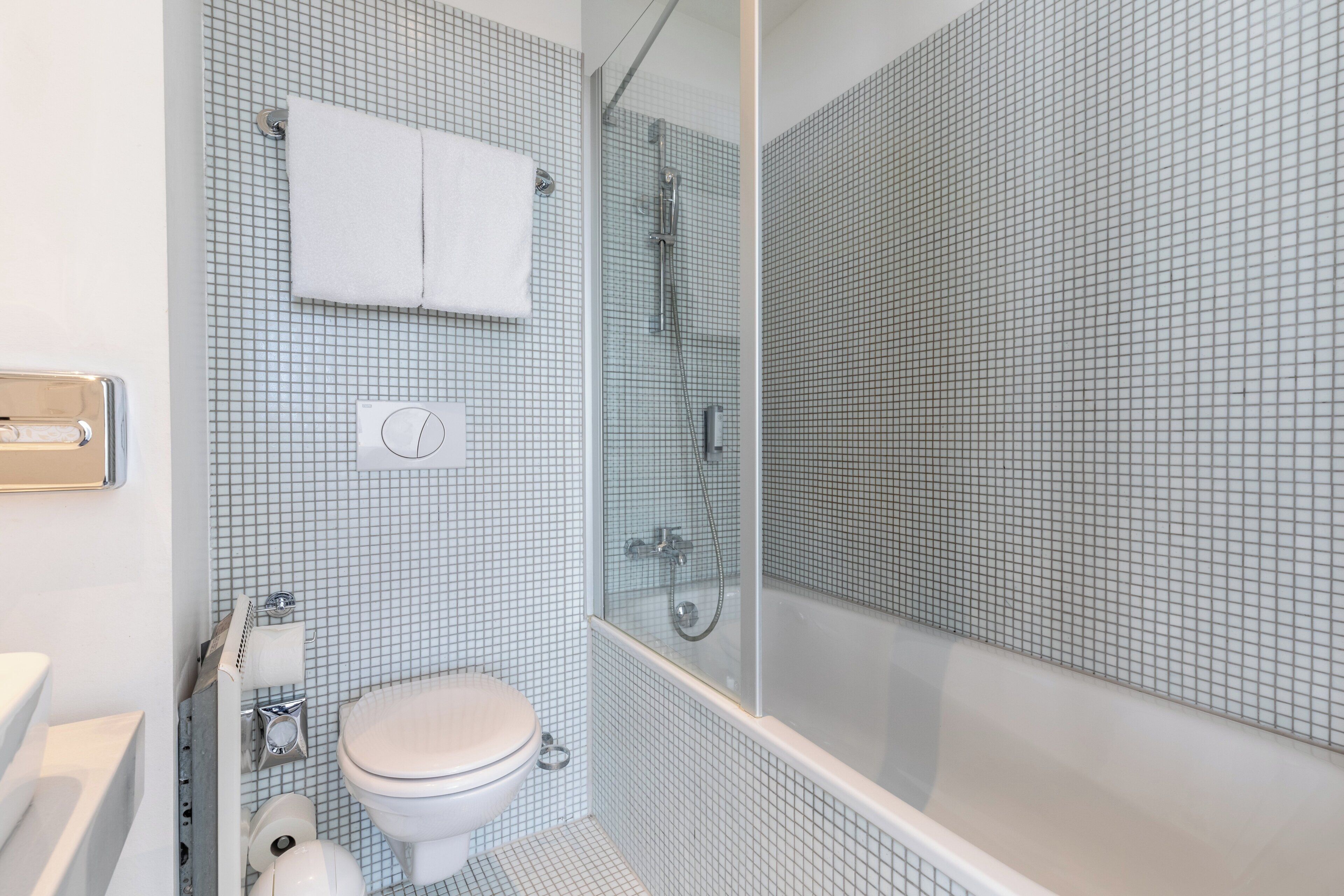 A bathroom with a toilet, a sink, a shower, and a glass-enclosed shower area.