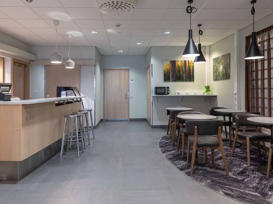 Un espace bar moderne avec des tabourets, un comptoir et un four à micro-ondes.