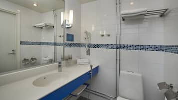 A modern bathroom with a double sink, a large mirror, a glass shower enclosure, and a towel rack.