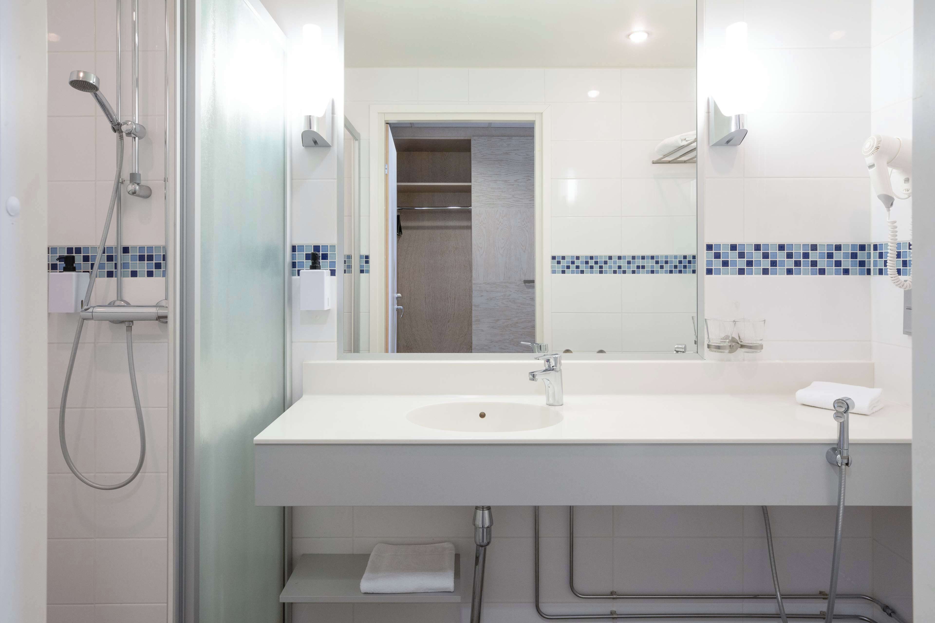 A modern bathroom with a white sink, a mirror, and a shower.