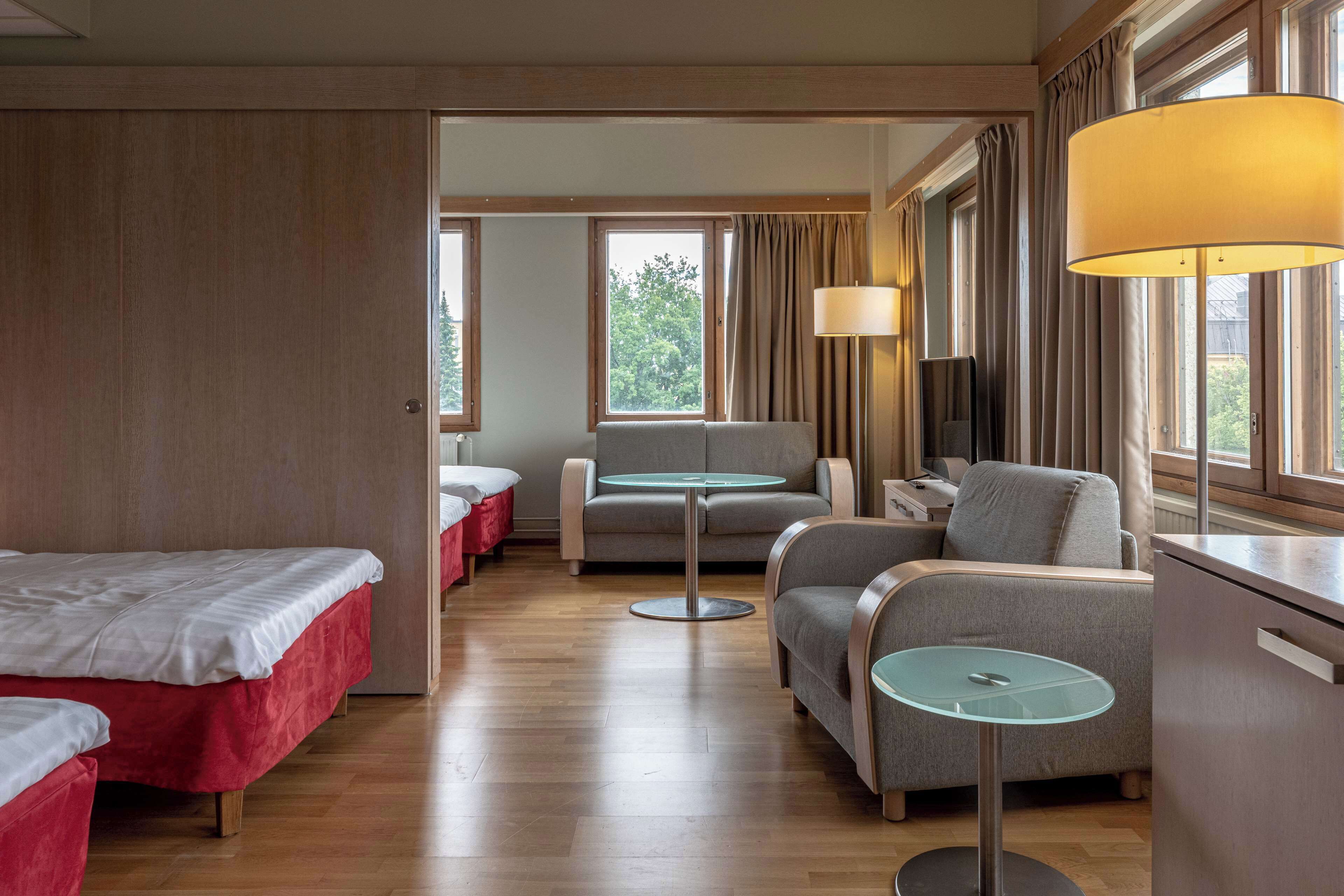 A hotel room with a bed, two armchairs, a small table, and a sofa.