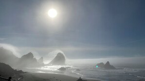 A beach with rocky formations and a clear sky.