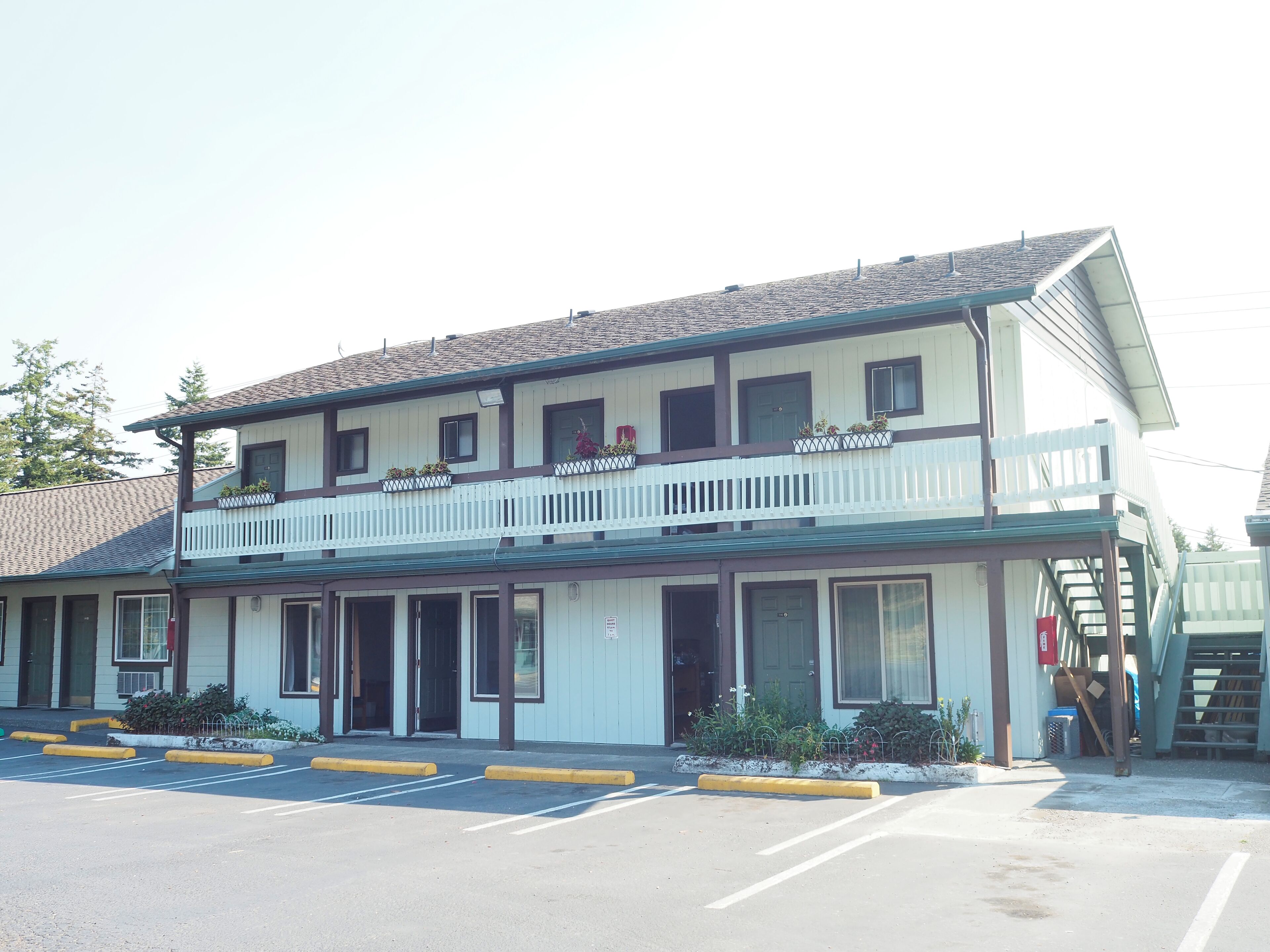 A two-story building with a balcony, a parking lot in front, and a sign indicating a motel.