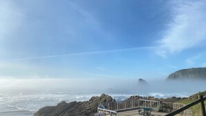 A coastal view with rocky terrain, a wooden walkway, and a picnic table.