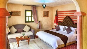 A cozy bedroom with a sofa, a bed, a small table, and a unique arched ceiling. - Riad Al Madina (Essaouira)