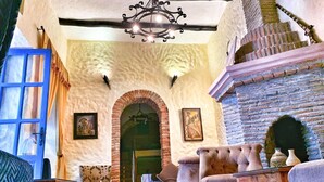 A cozy interior with a fireplace, wooden furniture, and a blue door. - Riad Al Madina (Essaouira)