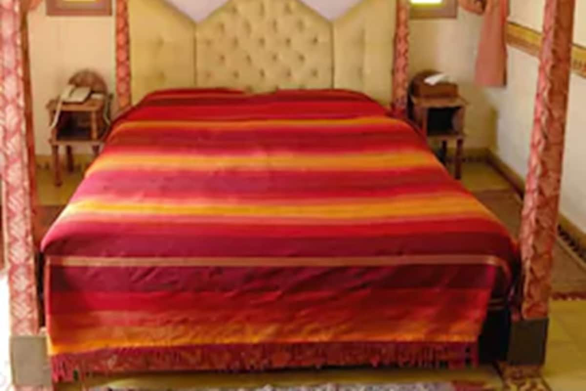 A bed with a striped bedspread, a tufted headboard, and a canopy.