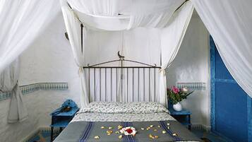 A room with a bed, a nightstand, a blue wall, and a white canopy.