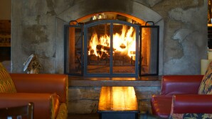 A stone fireplace with a glass door, a wooden bench, and leather sofas in a room. - Oregon Garden Resort (Silverton)
