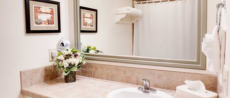 A bathroom with a large mirror, a sink, a towel rack, and a shower curtain.
