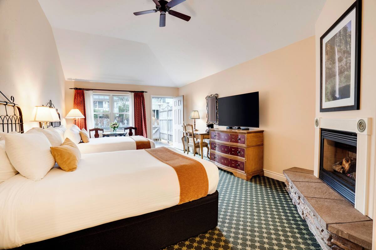 A hotel room with a large bed, a television, a fireplace, and a view of the outside.