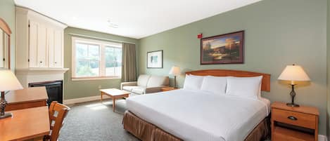 A hotel room with a large bed, a desk, a chair, a sofa, a nightstand, and a lamp.