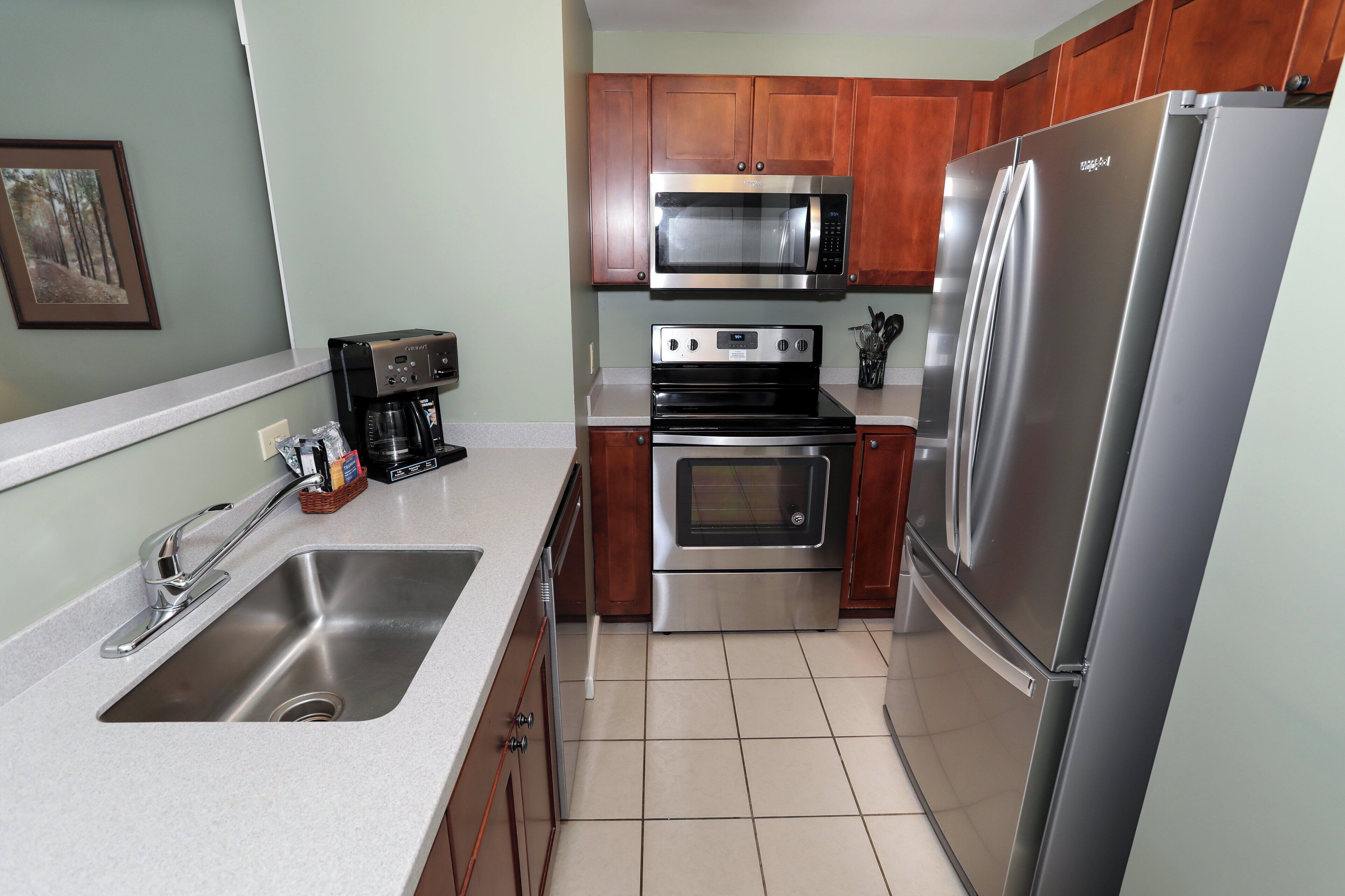 A kitchen with a stainless steel refrigerator, a microwave, an oven, and a sink.
