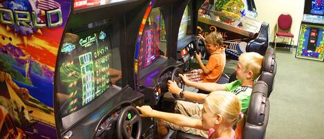 A group of children playing arcade racing games.