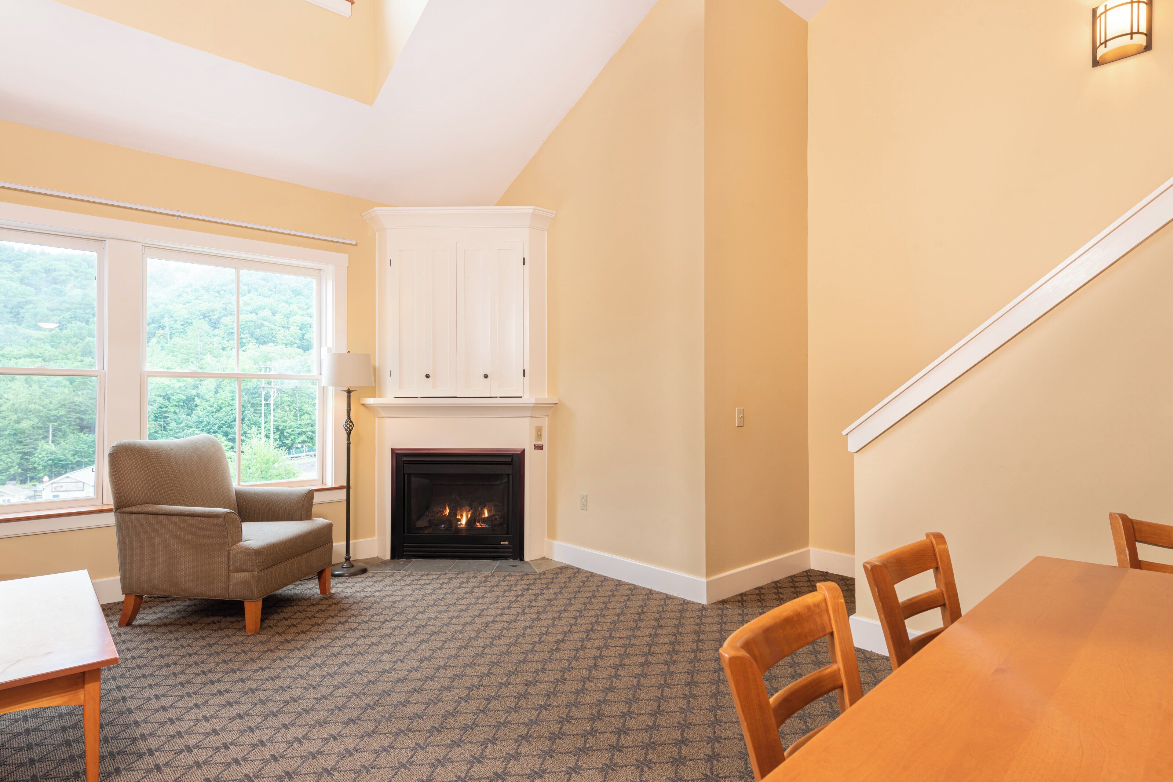 A room with a fireplace, a sofa, a dining table, and a view of the outdoors.