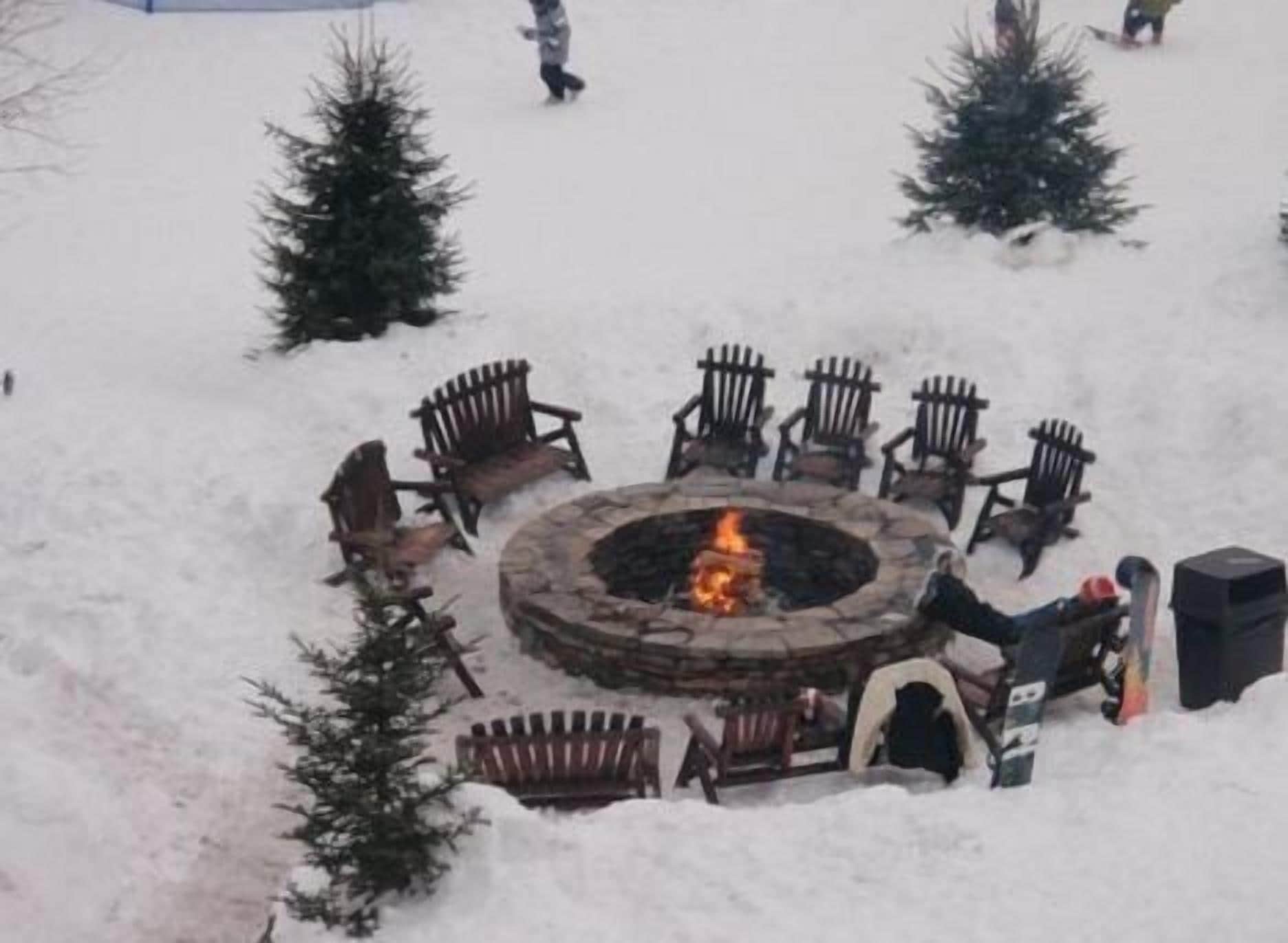 A circular outdoor seating area with a fire pit surrounded by wooden chairs.