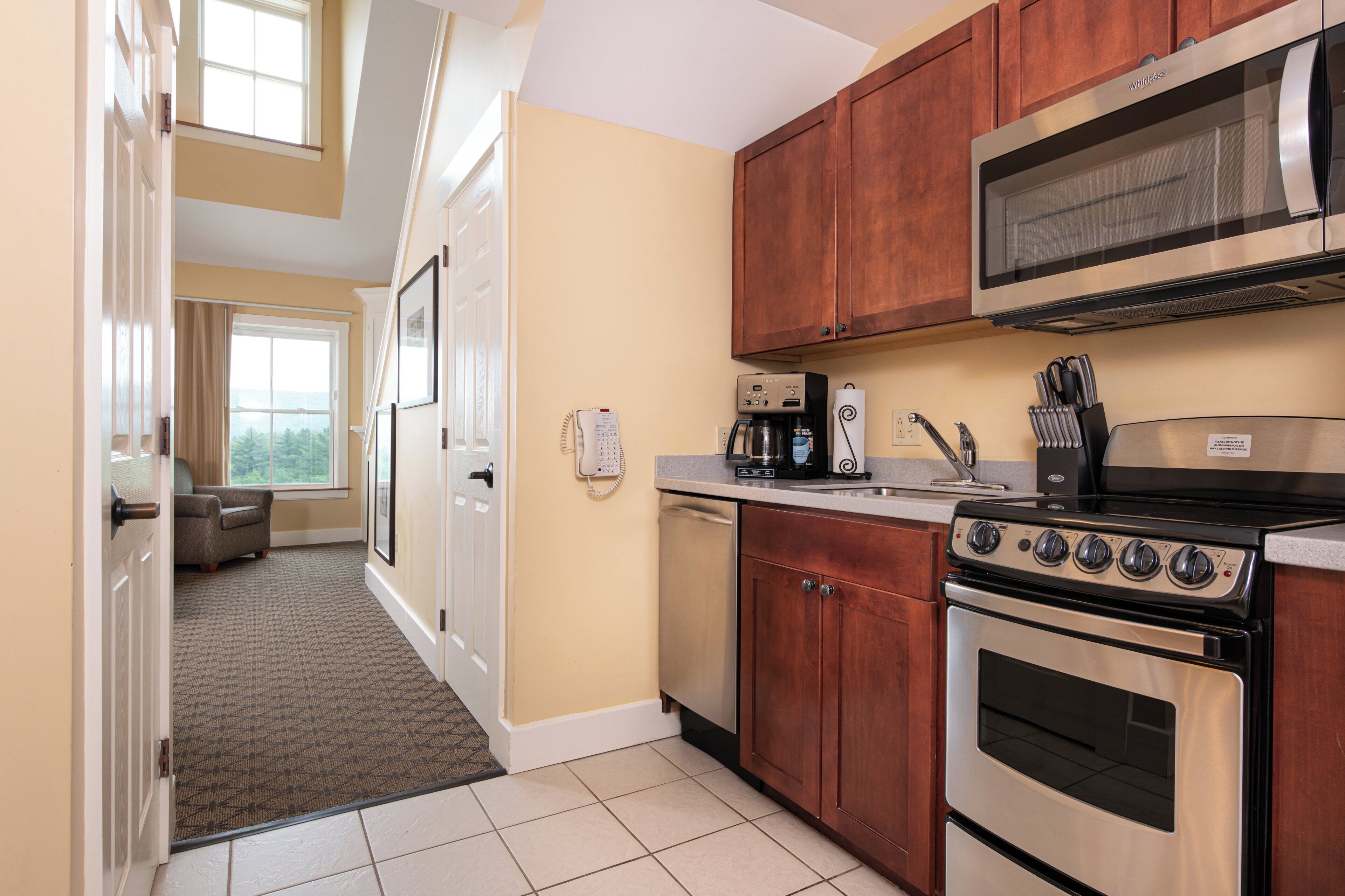 A kitchen with wooden cabinets, a stainless steel stove, a microwave, and a coffee maker.