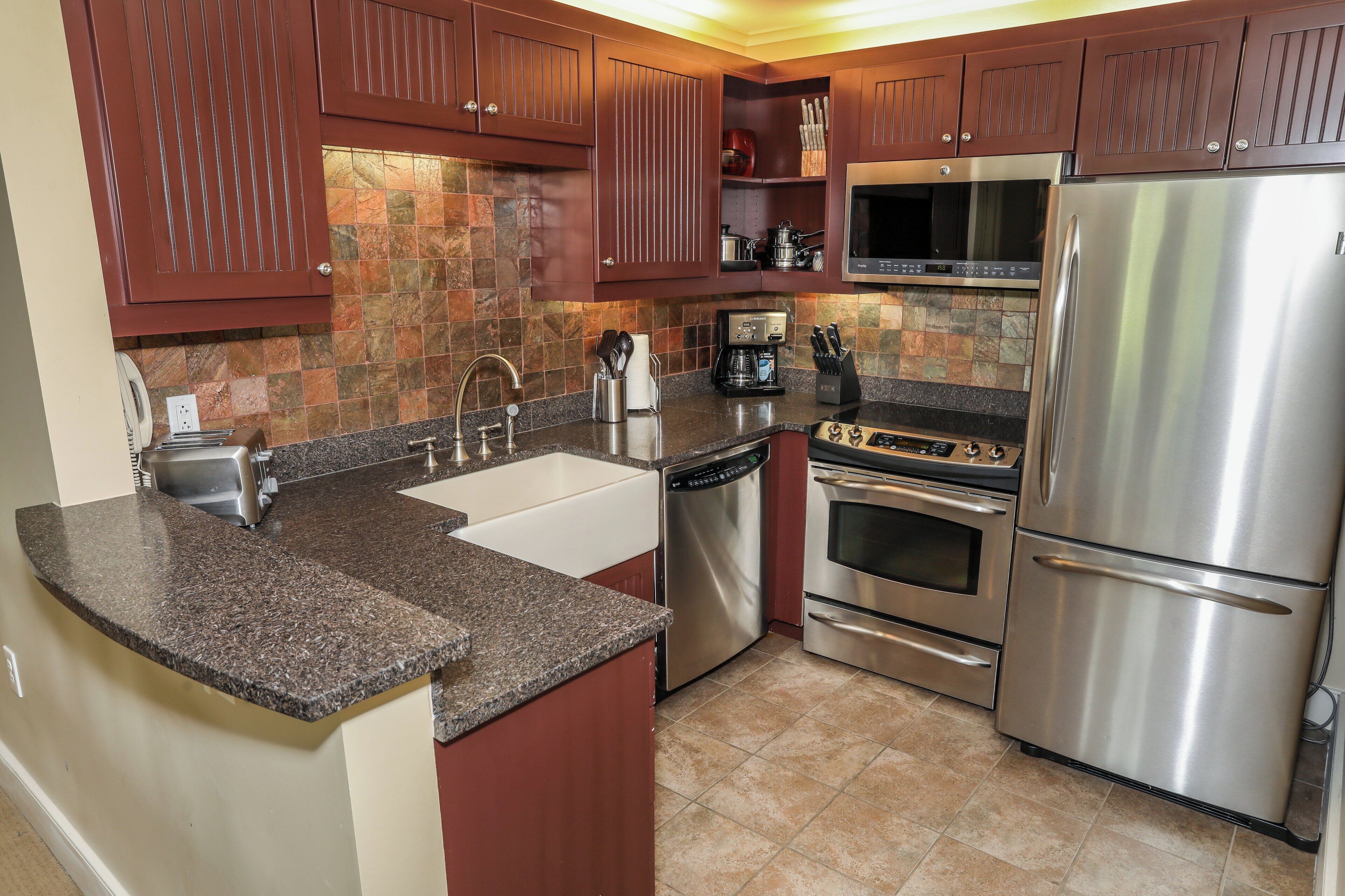 A kitchen with granite countertops, stainless steel appliances, and wooden cabinets.