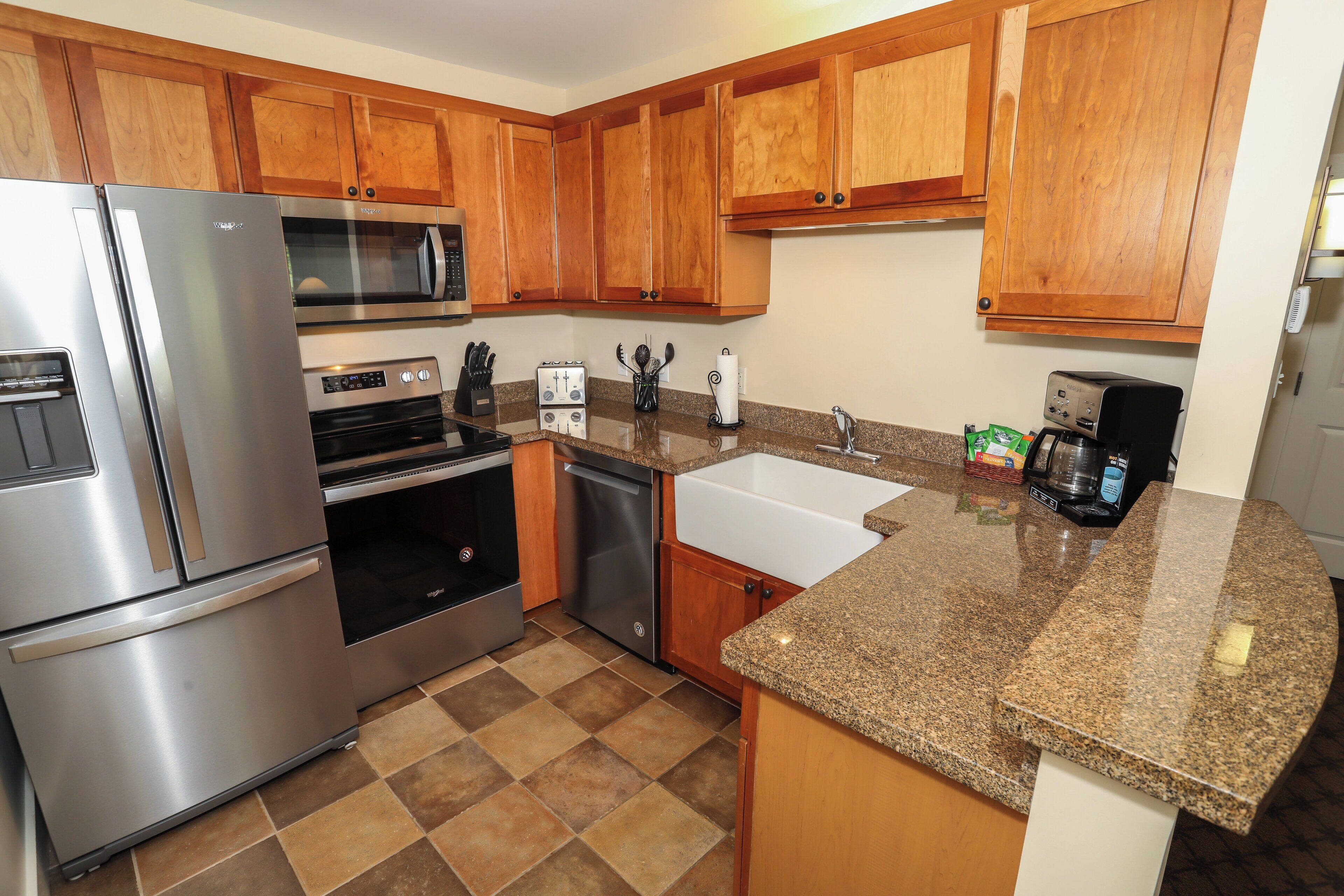 A kitchen with wooden cabinets, stainless steel appliances, a granite countertop, and a built-in oven.