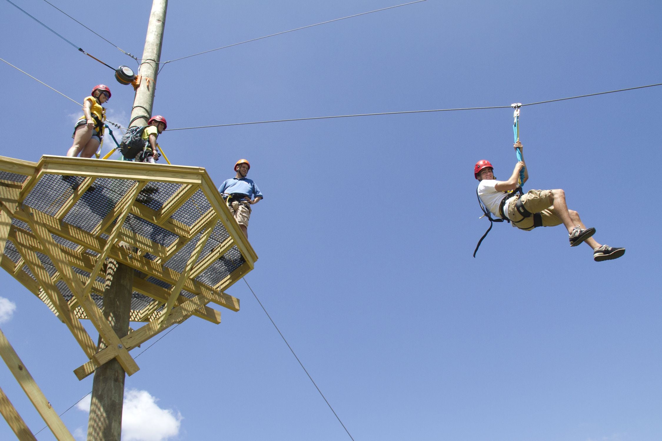 A zip-lining activity with participants and an instructor on a platform.