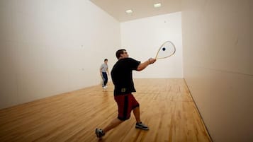 En squashbane med trægulv og hvide vægge.