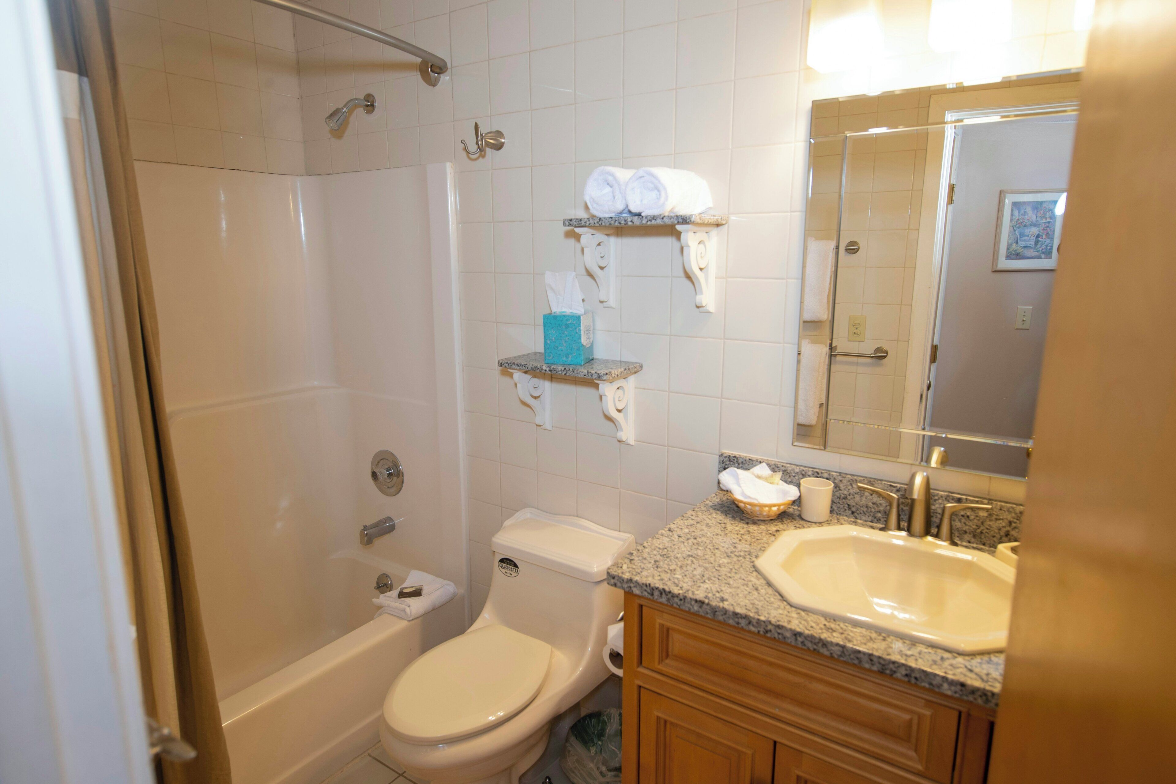 A bathroom with a bathtub, toilet, sink, and towel racks.