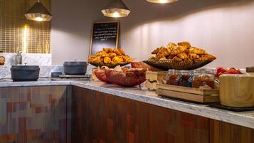 Un buffet de petit-déjeuner avec des croissants, un menu écrit à la craie et un éclairage moderne suspendu.