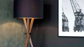 Een moderne woonkamer met een vloerlamp, een ingelijst foto op de muur en een bank.