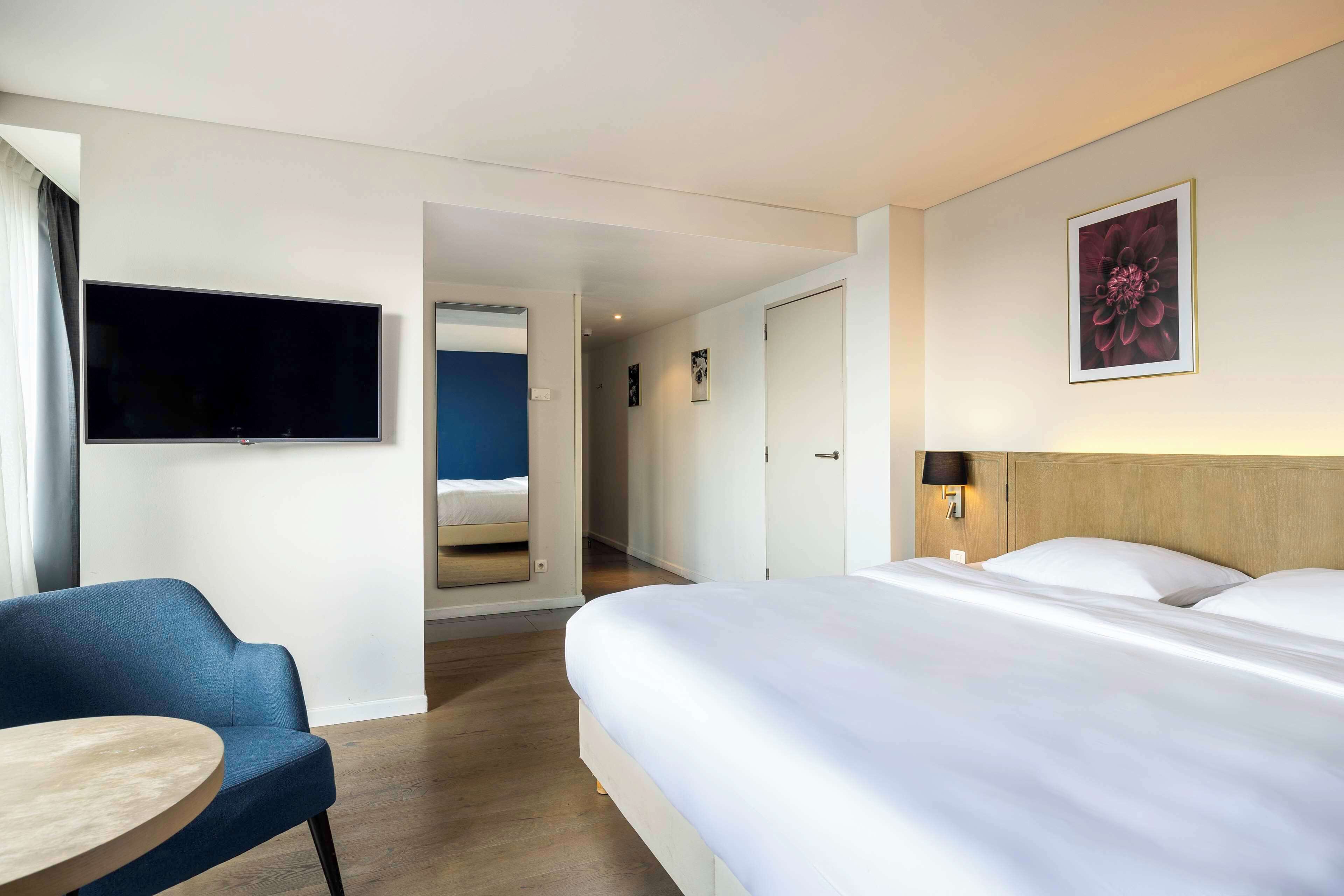 Una habitación de hotel con cama, televisor, escritorio y silla.