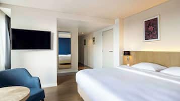 Una habitación de hotel con cama, televisor, escritorio y silla.
