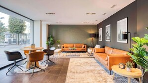 Un salon moderne avec un canapé en cuir, une table basse ronde et un coin repas comprenant des chaises et une table.