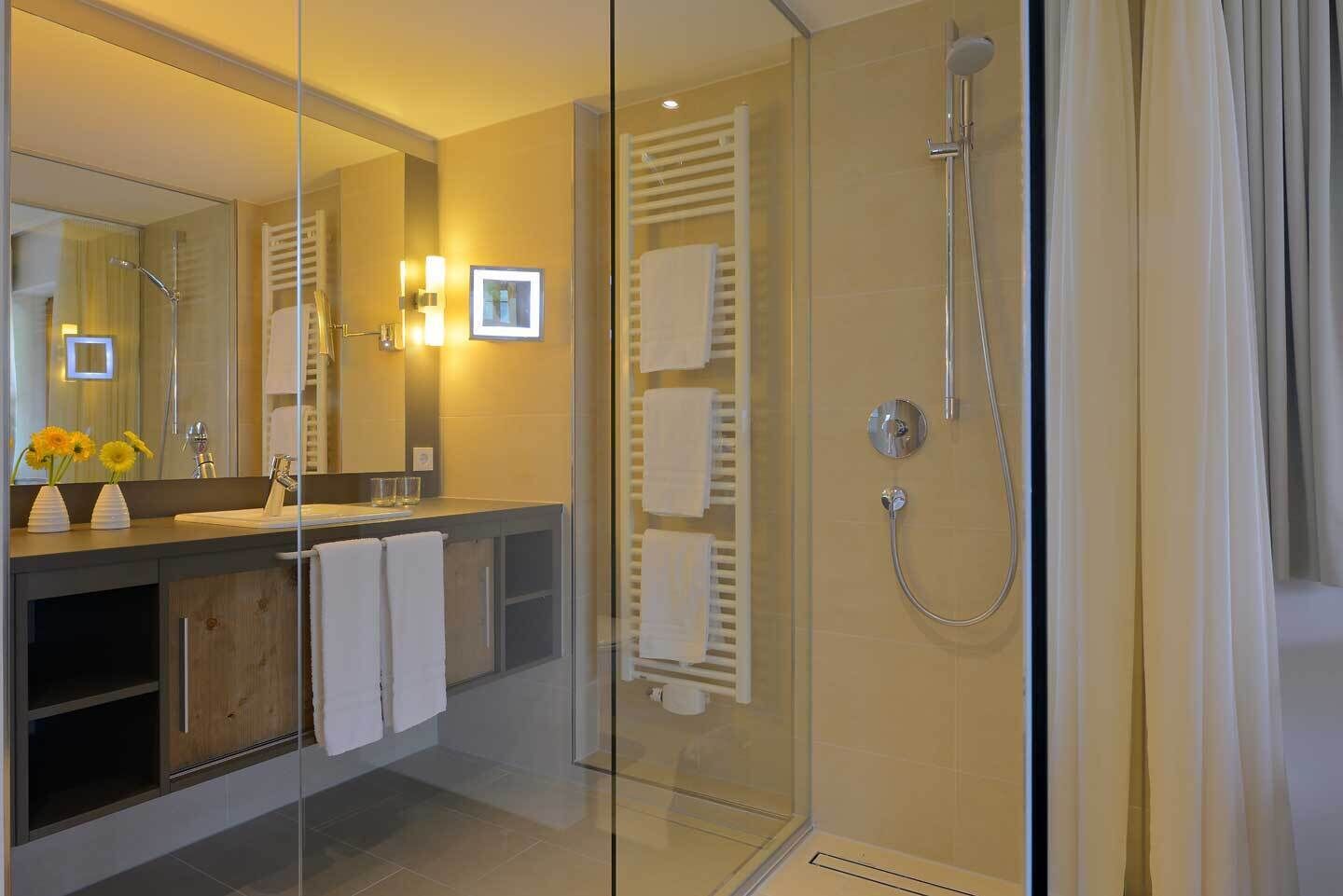 Un baño moderno con cabina de ducha de vidrio, tocador con espejo y lavabo.