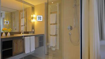 Un baño moderno con cabina de ducha de vidrio, tocador con espejo y lavabo.