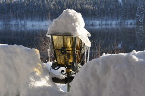Lumipeitteinen valaisinpylväs talvisessa maisemassa.