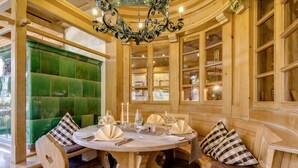 A round dining table with a white tablecloth, surrounded by wooden chairs and cushioned benches. - Boutique-Hotel Alemannenhof (Hinterzarten)