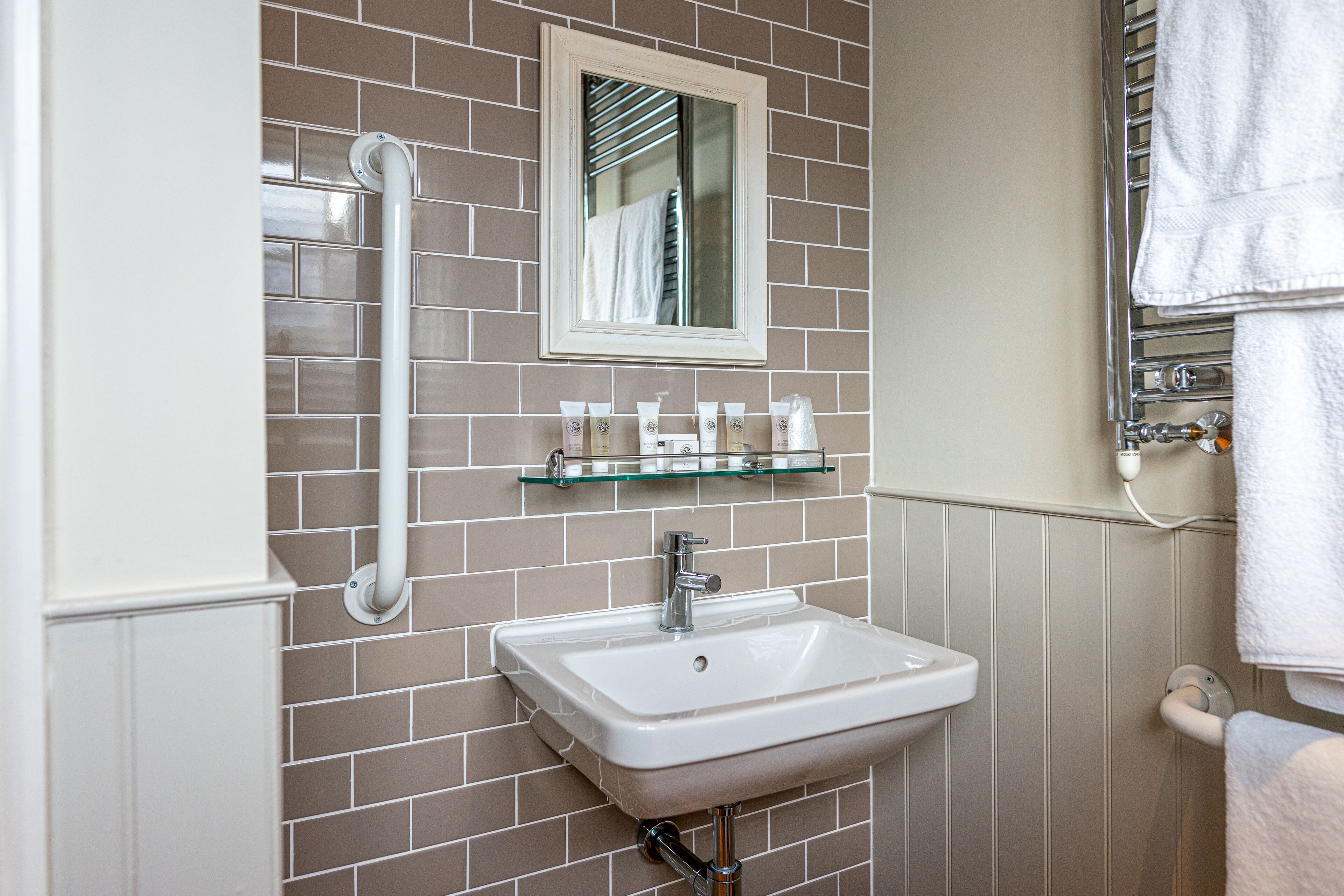 A bathroom with a white sink, a mirror, and a towel rack.
