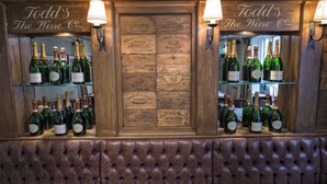 A bar area with a wooden sign reading "Todd's The Wine Co." and bottles of wine on shelves. - The Sun Inn (Faversham)
