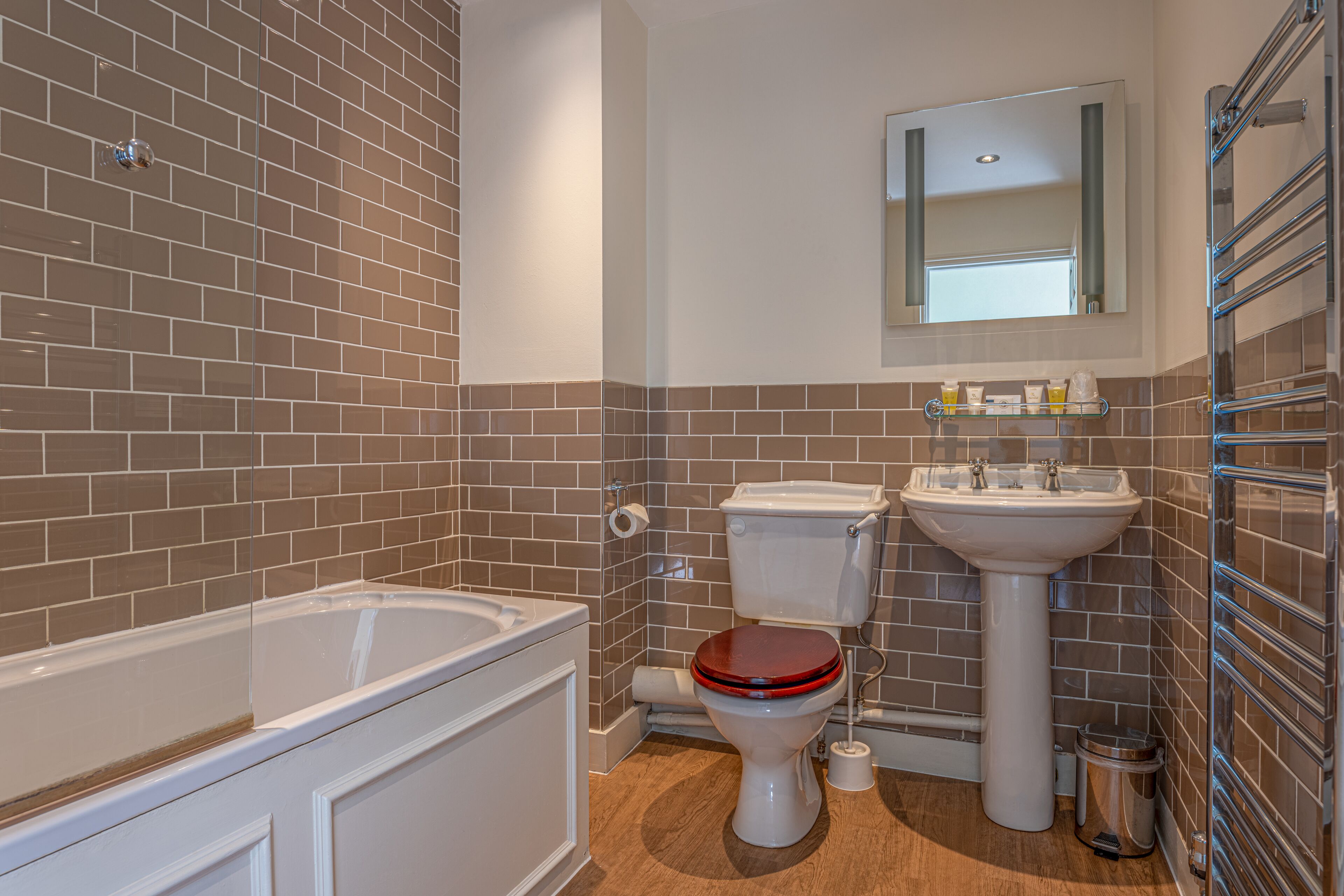 Ein Badezimmer mit Badewanne, Toilette, Waschbecken und Spiegel über dem Waschbecken.