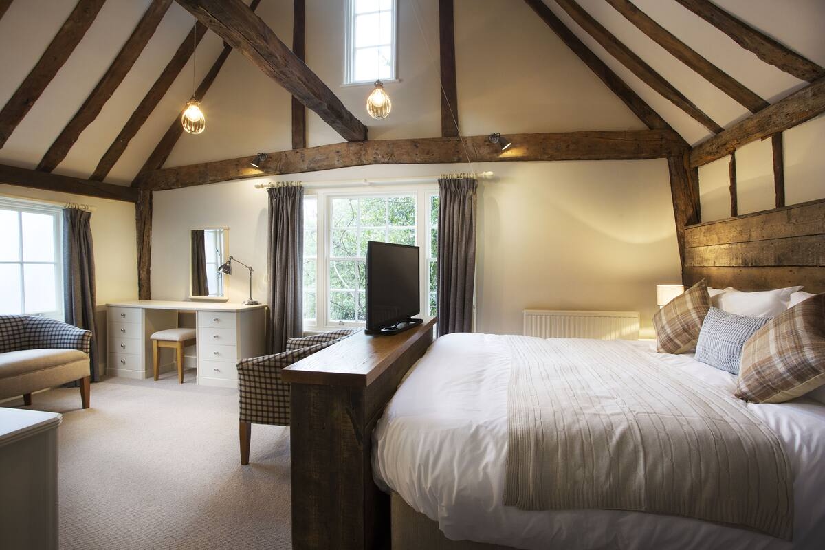 A bedroom with a bed, desk, chair, and a television.