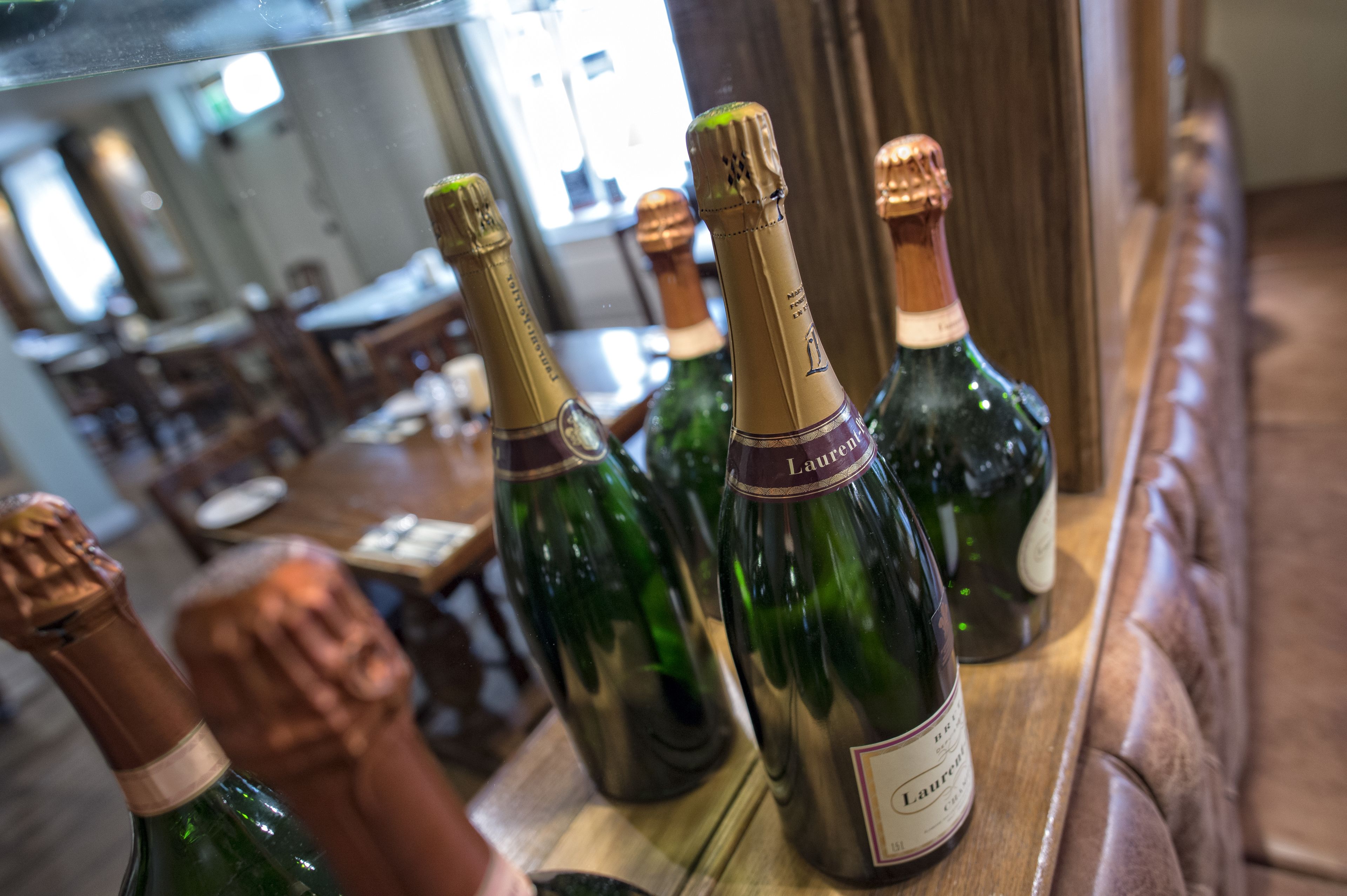 Een rij champagneflessen op een houten tafel in een restaurant.