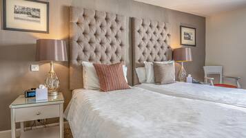 A hotel room with two beds, a nightstand with a lamp, and framed pictures on the wall.