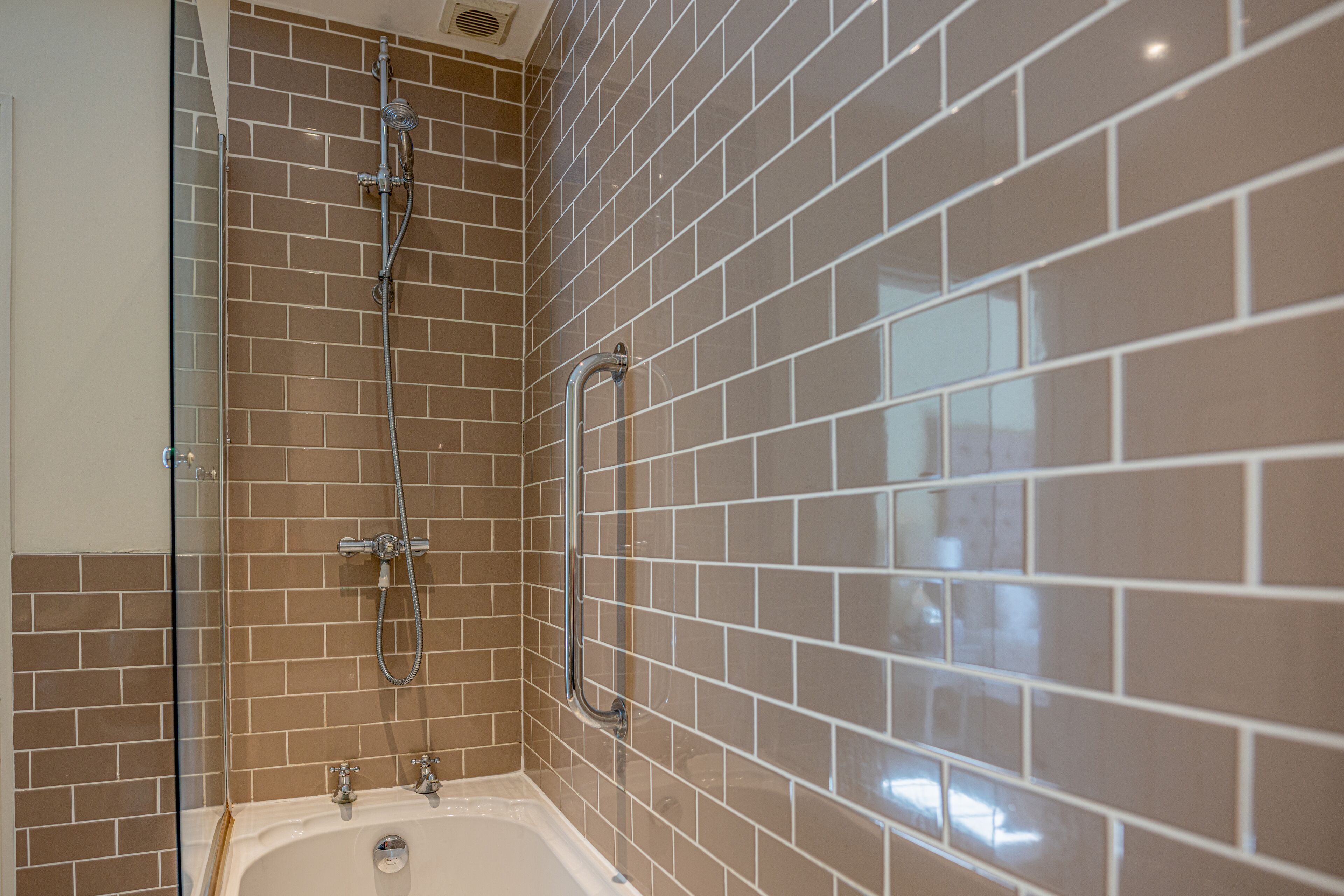 Une salle de bain avec une douche à parois de verre, une baignoire et des murs carrelés.