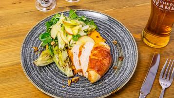 Une assiette de nourriture et un verre de bière sur une table en bois.